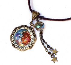 "A necklace with whimsical celestial charm featuring an embossed gold moon and sun pendant that's been accented with violet and pinked orange! Dangling alongside,a couple of star charms swing beneath a lustrous faceted glass bead of light turquoise! And a violet/moonstone-colored Swarovski crystal rhinestone sparkles from the half moons' chin! The artful pendant hangs from a faux suede necklace that has an extender chain to make it easy to find your perfect length! Add this one to your jewelry b Adjustable Bohemian Jewelry With Sun And Moon Design, Adjustable Spiritual Sun And Moon Jewelry, Whimsical Adjustable Gold Necklace, Adjustable Celestial Necklace With Star Charm, Celestial Adjustable Nickel-free Jewelry, Whimsical Pendant Charm Necklace, Adjustable Necklace With Round Moon Charm Pendant, Gold Star Charm Jewelry For Festival, Adjustable Sun And Moon Design Jewelry For Gifts