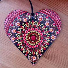 a heart shaped ornament on a wooden surface with beads and bead work