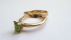 "Stunning set of 2 14K yellow gold stacking rings - a peridot solitaire ring and a unique wedding band. This set consists of 2 beautiful solid gold rings: The 1st is a rustic wedding band, with an uneven design that gives it a distinctive \"handmade\" look. It is forever changing, never looking the same. The 2nd ring has a sparkling green rectangular peridot set in a beautiful base. This can be an awesome engagement ring. This modern bridal ring set is perfect for a boho bride. The rings have a Yellow Gold Peridot Diamond Ring, Green Bezel Setting Stackable Rings For Wedding, Yellow Gold Peridot Stackable Rings For Anniversary, Yellow Gold Stackable Rings With Peridot, Stackable Peridot Anniversary Jewelry, Stackable Peridot Jewelry For Anniversary, Elegant Green Peridot Stackable Rings, Stackable Peridot Birthstone Ring For Anniversary, Green Peridot Stackable Rings