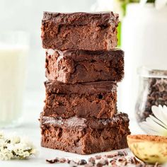 chocolate brownies stacked on top of each other next to a glass of milk and flowers