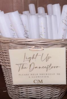 a basket filled with white candles sitting on top of a wooden table next to a sign that says, light up the dancefloor