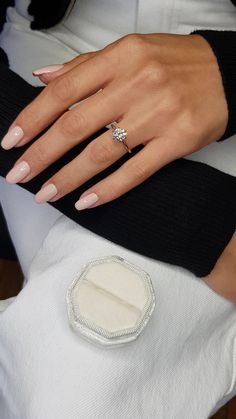 a woman's hand with a ring on top of her finger, sitting on a white cushion