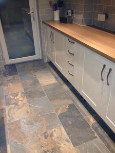 a kitchen with tile flooring and white cupboards on either side of the counter