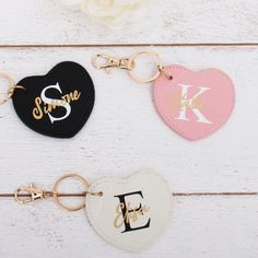 three personalized keychains are shown on a white wooden surface with flowers in the background