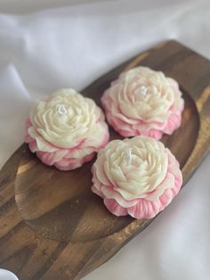 three pink and white flowers on a wooden spoon