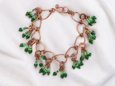 This lightweight copper beaded charm bracelet features 100% handmade copper links hung with multicolored green glass beaded charms This organic deco jewelry lends a sophisticated tropical accent to compliment your style and elevate any outfit. This bracelet is part of the Mangrove collection, inspired by the mangrove marshes of South Florida, with copper elements evoking the branching exposed roots and deep green accents evoking lush plant life that is beautifully cohesive and unique in the worl Elegant Green Wire Wrapped Beaded Bracelets, Green Metal Beaded Bracelets For Jewelry Making, Green Bracelet With Lobster Clasp, Bohemian Green Copper Jewelry, Green Wire-wrapped Bracelets With Round Beads, Green Wire Wrapped Bracelets, Green Wire Wrapped Bracelets With Round Beads, Green Wire Wrapped Czech Glass Jewelry, Green Bohemian Metal Beaded Bracelets