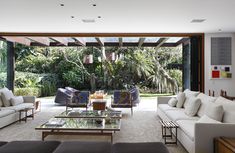 a living room with couches, tables and chairs in front of an open glass door