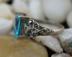 This is the perfect option for those who like cool, unique jewelry and the luxury, shine of silver,light blue. This ring is well made, cute and/or elegant in design, and very desirable. The ring is decorated with clear light blue stone in the sterling bezels. The ring is decorated with cz on the sides, but almost all cz are lost. ♥ There is a hallmark: 925. ♥The ring is in very good condition. ♥The size of the ring is 5 1/4. ♥The band of ring is curved. This item is pre-owned vintage and may sho Silver Topaz Ring With Rectangular Accent Stones, Silver Topaz Ring With Rectangular Blue Stone, Silver Blue Topaz Ring With Rectangular Stone, Silver Ring With Rectangular Blue Topaz, Silver Rings With Rectangular Blue Topaz, Blue Rectangular Topaz Ring With Accent Stones, Blue Topaz Ring With Accent Stones, Rectangular Shape, Rectangular Blue Topaz Ring With Accent Stones, Fine Jewelry Blue Rectangular Topaz Ring