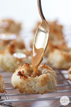 a person pouring sauce on top of some food that is on a wire rack and in the air