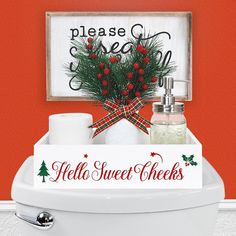 a white toilet sitting next to a red wall with a christmas sign on the side