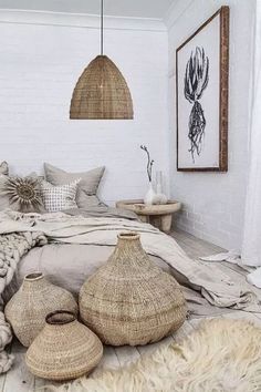 a bedroom with white brick walls and flooring is decorated in natural materials such as pillows, blankets, rugs and baskets