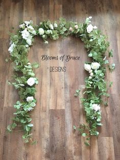 flowers and greenery arranged in the shape of a heart on a wooden floor that says blooms of grace designs