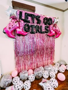 balloons and streamers are on the floor next to a pink curtain that says let's go girls