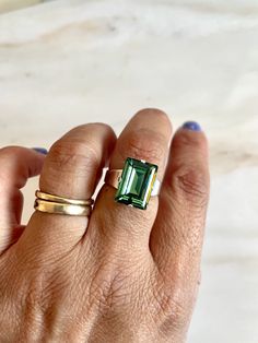 I am pleased to present a stunning cocktail ring that exudes the brilliance of a gemstone. The ring features a baguette cut Swarovski crystal carefully placed into a silver-plated adjustable band. The ring can be adjusted to fit various finger sizes, starting at about size 5. This piece of jewelry is versatile enough to be worn on special occasions or as a dazzling everyday accessory. The ring base is Nickel Free, ensuring safety and comfort for the wearer. Ships Free • Handmade in the USA Silver Sterling Emerald Ring With Baguette Cut, Silver Sterling Silver Emerald Ring Baguette Cut, Silver Sterling Baguette Cut Emerald Ring, Silver Sterling Silver Baguette Cut Emerald Ring, Modern Emerald Cut Crystal Ring, Adjustable Formal Crystal Ring With Gemstone, Formal Adjustable Gemstone Crystal Ring, Baguette Cut Topaz Ring As Gift, Adjustable Gemstone Crystal Ring For Formal Occasions