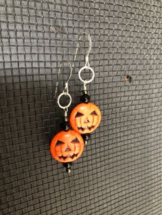 two carved pumpkins are hanging from earrings