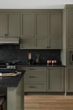 a kitchen with green cabinets and black counter tops