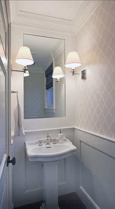 a bathroom with a sink, mirror and lights on the wall next to each other