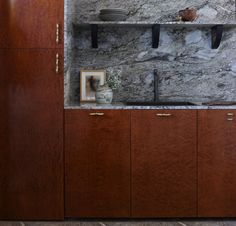 a kitchen area with wooden cabinets and marble counter tops, along with pots and pans on the shelves