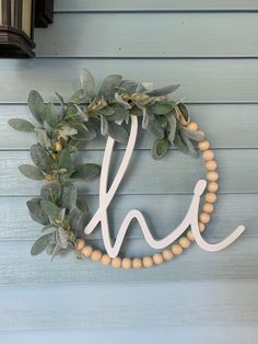 a wreath with the letters h and w hanging on a blue painted wall next to a light fixture