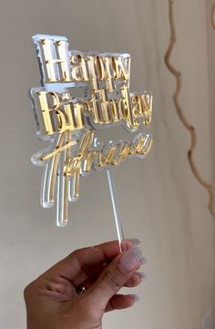 a person holding up a happy birthday cake topper