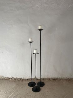 three black and white candles sitting on top of each other in front of a wall