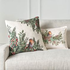 two pillows sitting on top of a couch next to each other in front of a white wall