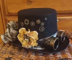 This is a custom made Steampunk Top Hat with silver colored Goggles. A sprinkle of brass gears, white mums, greenery, and gold mums set off the black of the hat. A clockwork owl nestles in the gold petals. A wide plaid band and bow gives it a finishing touch on the felt hat.  It is the perfect accessory for your steampunk costume. The hat is pressed felt with a suede texture It measures: 12.4 x 8.7 x 5.4 inches Punk Hats, Halloween Forest, Mad Hatter Top Hat, Punk Top, Steampunk Top, Girl Gamer, Steampunk Top Hat, Owl Hat, Punk Hair