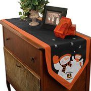 an orange and blue christmas table runner with snowmen on it next to a potted plant