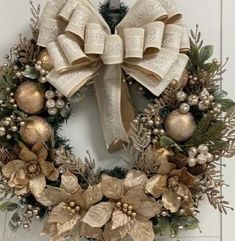 a christmas wreath hanging on the front door with gold and silver ornaments, holly leaves and bells