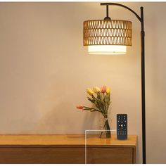 a lamp that is on top of a dresser next to a vase with flowers in it