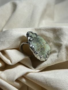 Large melted metal handmade ring with green natural handpicked stone. I personally really love stand out pieces, and I promise you won't find anything similar to this one! - Style: Organic, Irregular Shape - Size: 5.5 (50-51 mm) MATERIALS: - Copper - 96 % Tin and 4% Silver alloy - Handpicked Raw Stone FEATURES: - Water Resistant: Designed to withstand everyday wear, this ring is water resistant 💧 - Non-Tarnish: Made with high-quality materials, it won't tarnish over time ✨ CARE INSTRUCTIONS: To Green Open Ring Made Of Metal, Green Metal Open Ring, Bohemian Green Metal Rings, Green Crystal Ring With Large Stone For Gift, Green Crystal Ring Metal Gift, Artisan Green Ring As Gift, Artisan Green Ring Gift, Green Crystal Healing Ring, Handmade Green Prehnite Jewelry