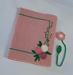 a pink knitted cloth with flowers on it and a green string attached to the side