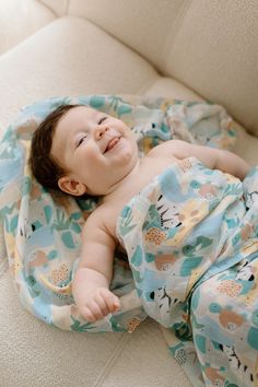 a smiling baby laying on top of a couch