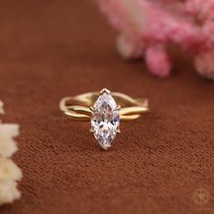 a close up of a ring on a table with flowers and shells in the background