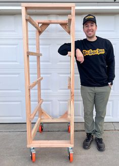 a man standing in front of a wooden rack holding his thumb up to the camera