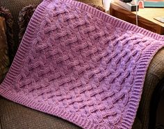 a pink knitted blanket sitting on top of a couch