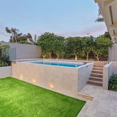 an outdoor swimming pool surrounded by grass and bushes with stairs leading up to the side