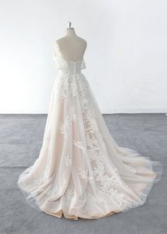 a white wedding dress on a mannequin in front of a white wall and floor