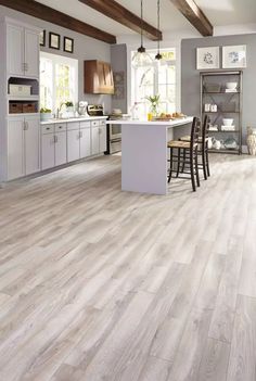 an open kitchen with white cabinets and wood flooring, along with a breakfast nook