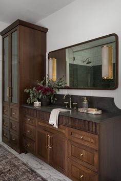 a large bathroom with wooden cabinets and marble counter tops, along with a rug on the floor