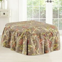 a large round ottoman covered in a floral print fabric with pleated skirting on the bottom