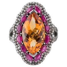 An epitome of opulence and sophistication, the 11.34 Carat Diamond, Golden Topaz, and Ruby Cocktail Ring is a true marvel of jewelry design. At its core, an extraordinary golden topaz captivates with its rich, amber hue and impeccable clarity. Weighing 11.34 carats, this stunning gemstone is masterfully faceted to reflect light with mesmerizing brilliance, exuding a warm, radiant glow. Surrounding the golden topaz are vibrant rubies, meticulously placed to create a striking contrast. Each ruby i