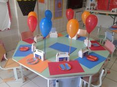 a table with some balloons on top of it in a room filled with other tables and chairs