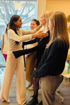 two women are helping another woman put on her tights while others look on in the background