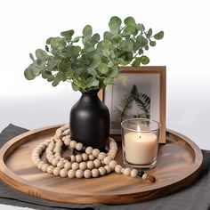 a wooden tray with a candle and some beads on it, next to a photo frame