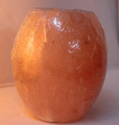 a large orange rock sitting on top of a white cloth covered table next to a lamp