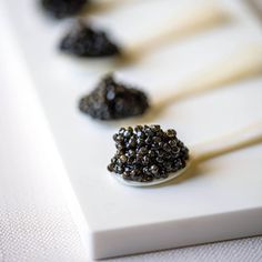 several spoons filled with blackberries on top of a white table