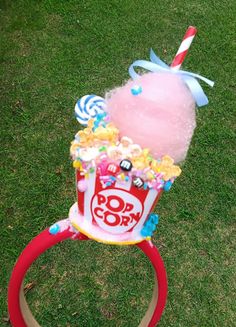 a pink cupcake with candy and candies in it sitting on top of a red ring