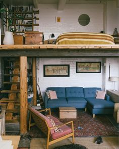 a loft bed with a couch underneath it and bookshelves on the wall above