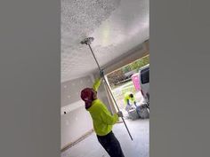 a man in a yellow shirt is cleaning the ceiling